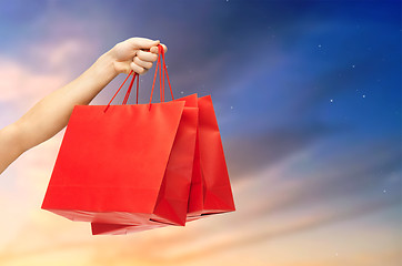 Image showing close up of male hand holding red shopping bags