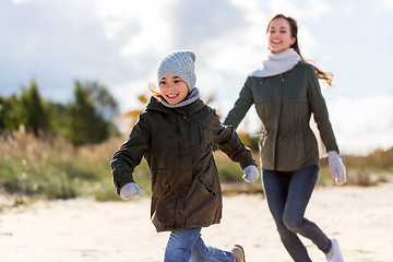 Image showing happy family running along autumn beach