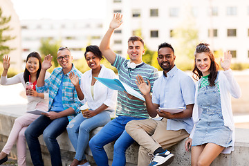 Image showing students with notebook waving hands outdoors