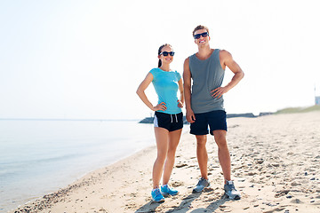 Image showing happy couple in sports clothes and shades on beach