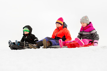 Image showing happy little kids sliding on sleds in winter