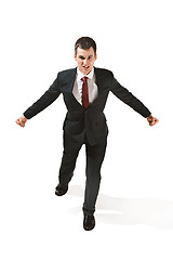 Image showing Above front portrait of a businessman with very serious face. Confident professional jumping in the foreground of the camera.