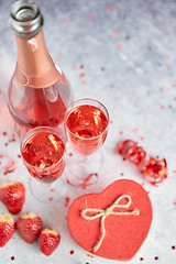 Image showing Bottle of rose champagne, glasses with fresh strawberries and heart shaped gift