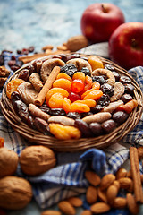 Image showing Composition of dried fruits and nuts in small wicker bowl placed on stone table