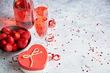 Image showing Bottle of rose champagne, glasses with fresh strawberries and heart shaped gift