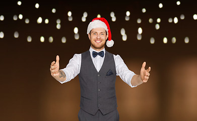 Image showing happy man in santa hat holding something imaginary