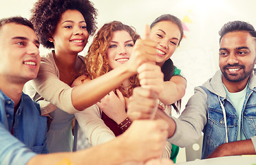 Image showing happy office workers doing teamwork gesture