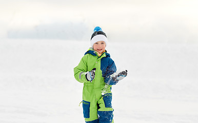 Image showing happy little boy playing with snow in winter