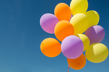 Image showing close up of colorful helium balloons in blue sky