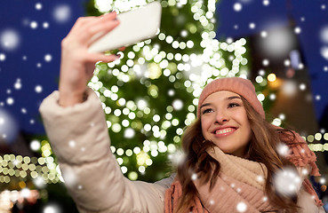 Image showing young woman taking selfie over christmas tree