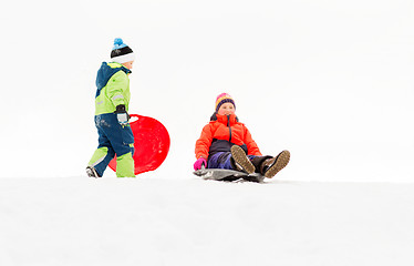 Image showing happy kids sliding on sleds down hill in winter