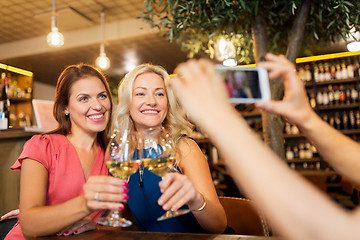 Image showing woman picturing friends by smartphone at wine bar