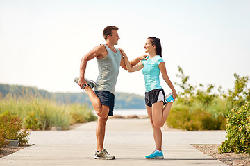 Image showing smiling couple stretching legs on beach