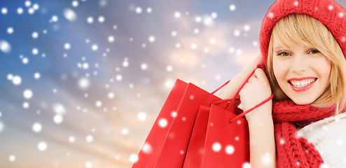 Image showing woman with red shopping bags over snow background