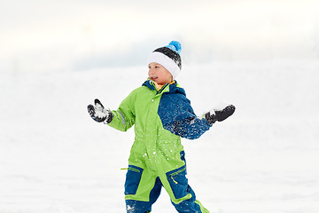 Image showing happy boy playing and throwing snowball in winter