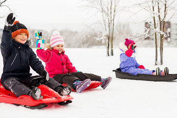 Image showing happy little kids sliding on sleds in winter