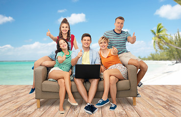 Image showing friends with laptop sit on sofa and show thumbs up
