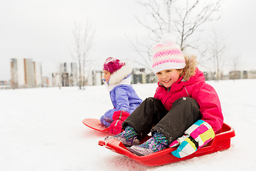 Image showing happy little girls on sleds outdoors in winter