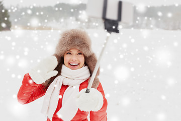 Image showing happy woman with selfie stick outdoors in winter