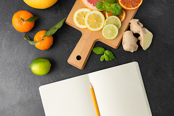 Image showing close up of fruits and notebook on slate table top