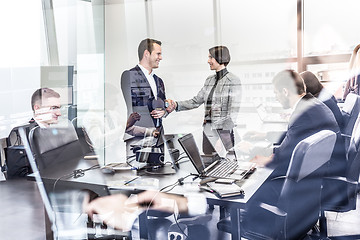 Image showing Business people shaking hands in moder corporate office.