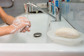 Image showing The child carefully washes his hands with soap, in the foreground a bar of soap