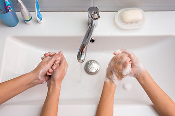 Image showing Two people wash their hands in the sink, top view