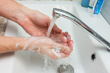 Image showing A man washes his hands from the thick suds