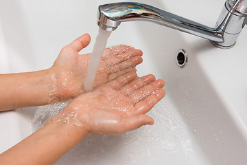 Image showing Children\'s hands under a strong stream of water from the mixer in the bathroom