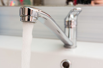 Image showing Faucet in the bathroom, water pours out of it