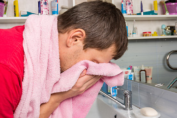 Image showing Man wipes his face with a towel in the bathroom
