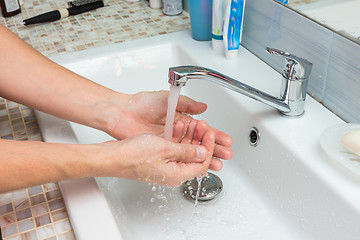 Image showing A man washes the wound under the tap