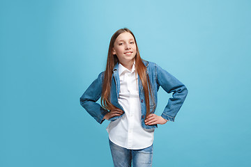 Image showing The happy teen girl standing and smiling against blue background.