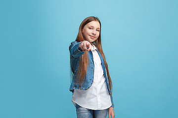 Image showing The happy teen girl pointing to you, half length closeup portrait on blue background.