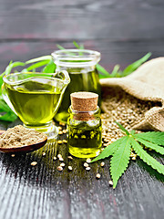 Image showing Oil hemp in two jars and sauceboat on dark board