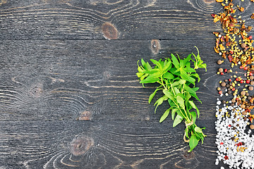 Image showing Savory leaves with spices on black wooden board