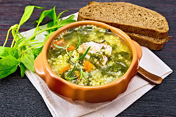 Image showing Soup with couscous and spinach in clay bowl on table