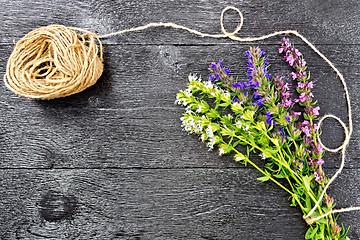 Image showing Savory leaves and flowers with twine on black board