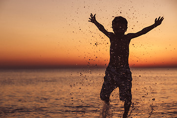 Image showing One happy little boy playing on the beach at the sunset time.