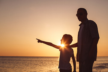 Image showing Father and son playing on the beach at the sunset time.