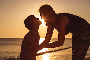 Image showing Mother and son playing on the beach at the sunset time.