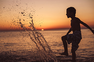 Image showing One happy little boy playing on the beach at the sunset time.