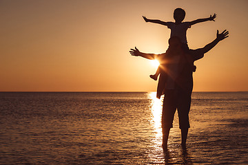 Image showing Father and son playing on the beach at the sunset time.