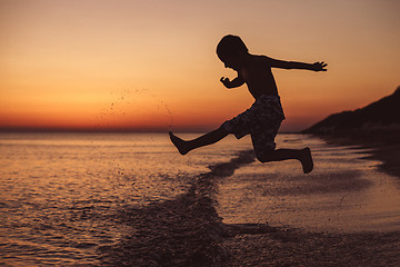 Image showing One happy little boy playing on the beach at the sunset time. 