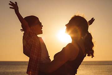 Image showing Mother and son playing on the beach at the sunset time.