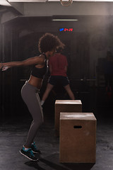 Image showing black female athlete is performing box jumps at gym