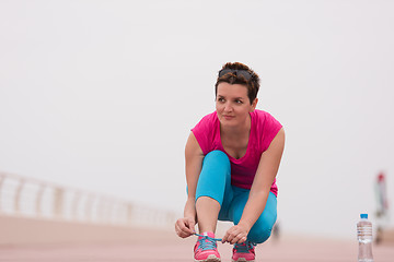 Image showing Young woman tying shoelaces on sneakers