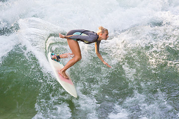 Image showing Atractive sporty girl in neoprene shorty wave surfing.