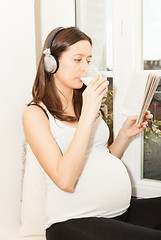 Image showing pregnant women drink a glass of milk and listening to music