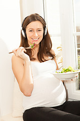 Image showing pregnant woman eat salad and listening to music